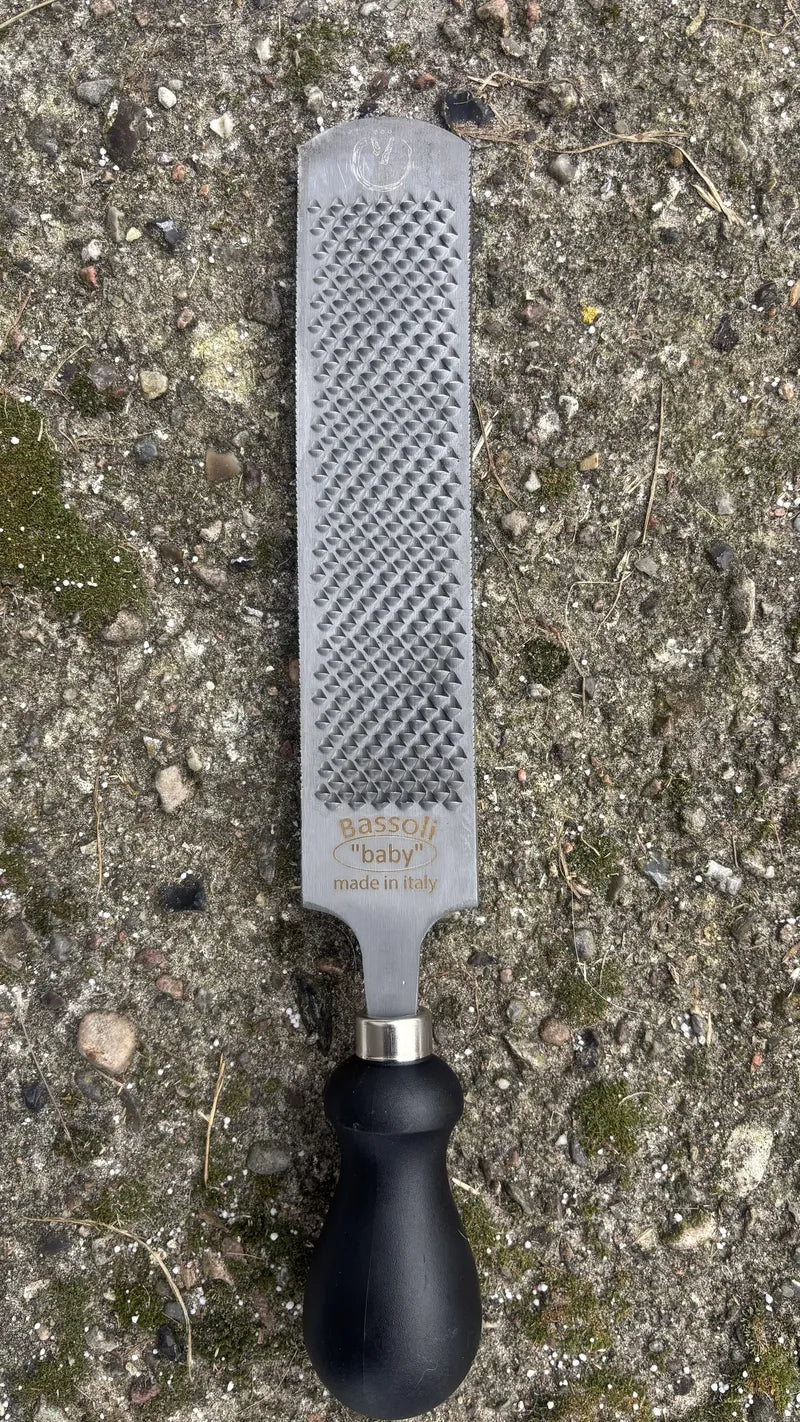 GoBarhuf Mini-Raspel "Baby" von Bassoli mit schwarzem ergonomischem Griff auf Naturboden.