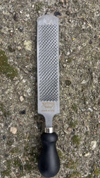 GoBarhuf Mini-Raspel "Baby" von Bassoli mit schwarzem ergonomischem Griff auf Naturboden.